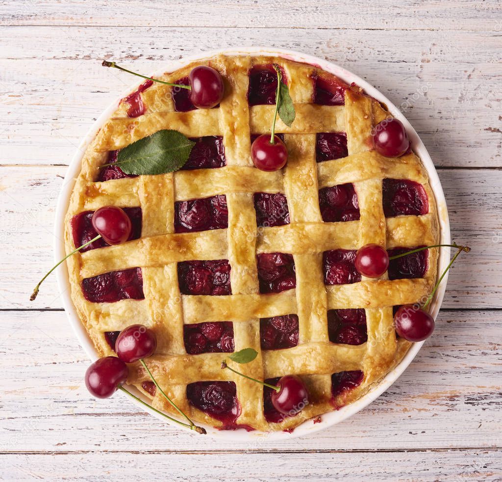 Close-up view of Delicious Homemade Cherry Pie with a Flaky Crust on rustic wooden white background. Top View