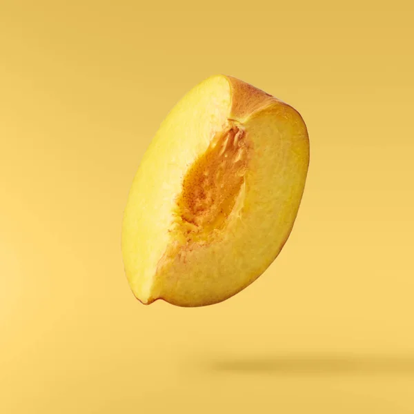 Flying fresh ripe peach  isolated on yellow background. Concept of food levitation, high resolution image