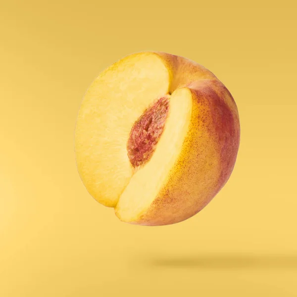 Flying fresh ripe peach  isolated on yellow background. Concept of food levitation, high resolution image