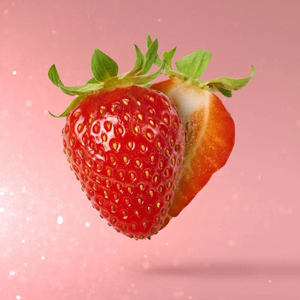 Flying Fresh tasty ripe strawberry with green leaves at light pink background.  Food levitation concept. Creative food layout, High resolution image