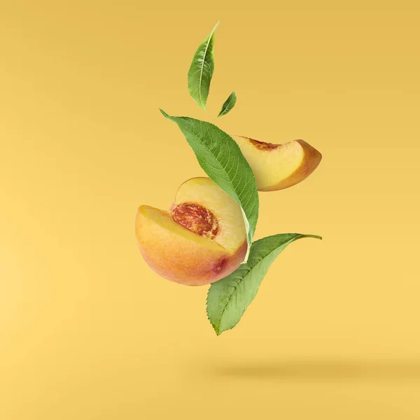 Fliegender Frischer Reifer Pfirsich Mit Grünen Blättern Auf Gelbem Hintergrund — Stockfoto