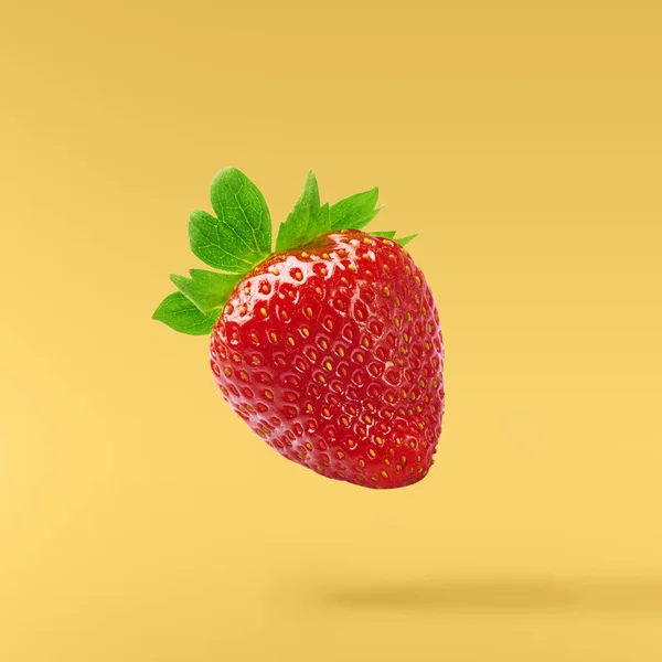 Flying Fresh tasty ripe strawberry with green leaves at yellow background.  Food levitation concept. Creative food layout, High resolution image