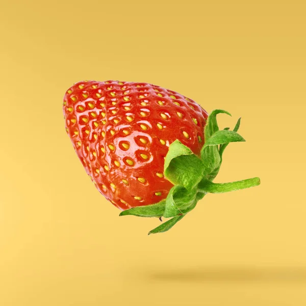 Flying Fresh tasty ripe strawberry with green leaves at yellow background.  Food levitation concept. Creative food layout, High resolution image