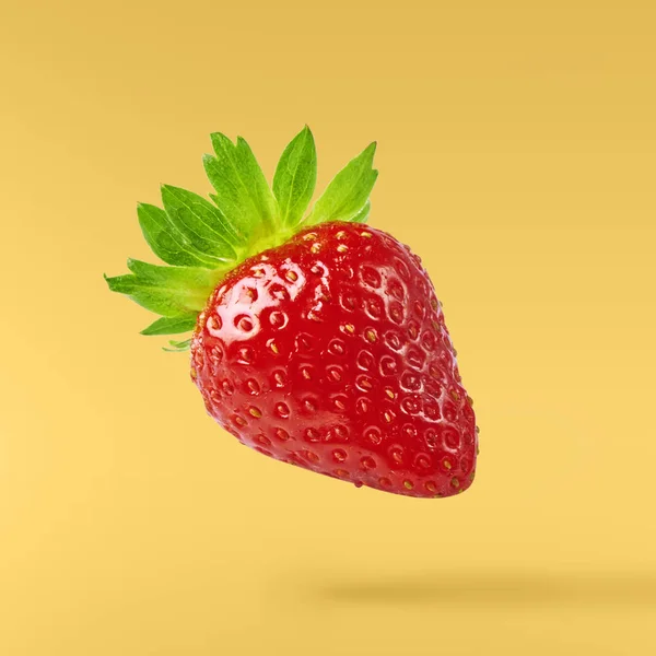 Flying Fresh tasty ripe strawberry with green leaves at yellow background.  Food levitation concept. Creative food layout, High resolution image