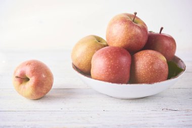 Taze meyve suyu olgun kırmızı elmalar ahşap beyaz masada kasede