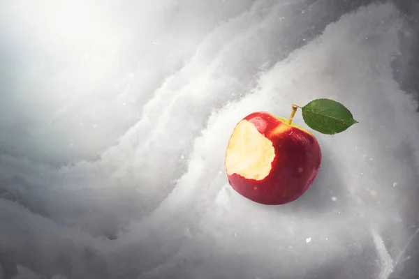 Fairy tale tale concept with poisoned bitten red apple laying on marble, sunlight and defocused falling snow, top view, high quality image. Once upon a time.