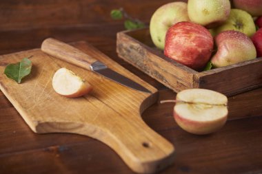 Ahşap kutusunda, taze olgun elma ahşap kahverengi zemin kurulu bıçak ve elma yarısı ile kesme
