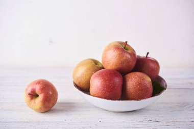 Taze meyve suyu olgun kırmızı elmalar ahşap beyaz masada kasede
