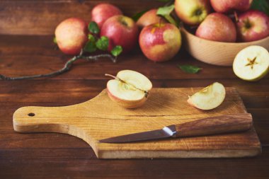 Kase, taze olgun elma ahşap kahverengi zemin kurulu bıçak ve elma yarısı ile kesme