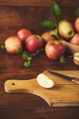 Kase, taze olgun elma ahşap kahverengi zemin kurulu bıçak ve elma yarısı ile kesme