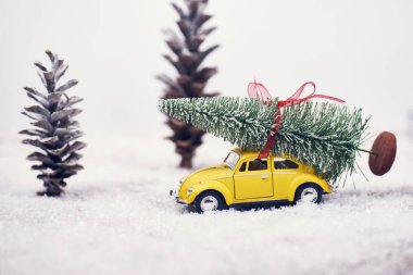 Sarı oyuncak araba kar ile Noel ağacına