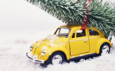 Sarı oyuncak araba kar ile Noel ağacına
