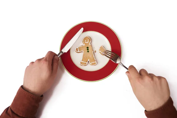 Man\'s hands holding fork and knife with gingerbread man