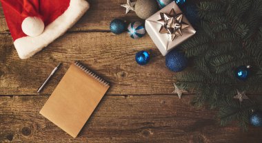 Hediye kutusu, süslemeleri, kırmızı şapka ve defter ile Noel ağacı