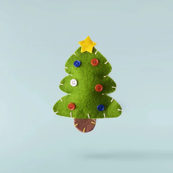 Christmas concept.  Creative Christmas conception made by falling in air green christmas cuddly tree over blue background. Minimal concept