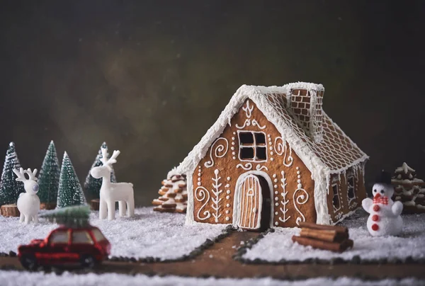 Homemade gingerbread house. Christmas concept. gingerbread house, cookies, tiny car toy with tree and deer with christmas tree at background