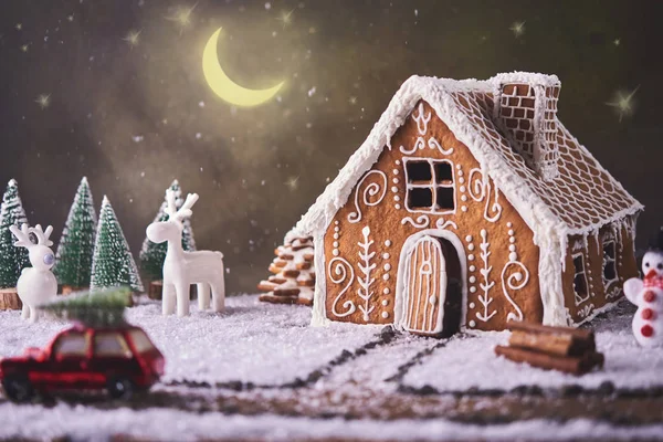 Homemade gingerbread house. Christmas concept. gingerbread house, cookies, tiny car toy with tree and deer with christmas tree at background