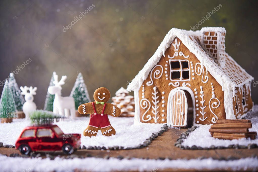 Homemade gingerbread house. Christmas concept. gingerbread house, cookies, tiny car toy with tree and deer with christmas tree at background