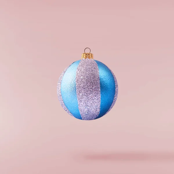 Christmas concept.  Creative Christmas conception made by falling in air shiny bauble over pink background. Minimal concept