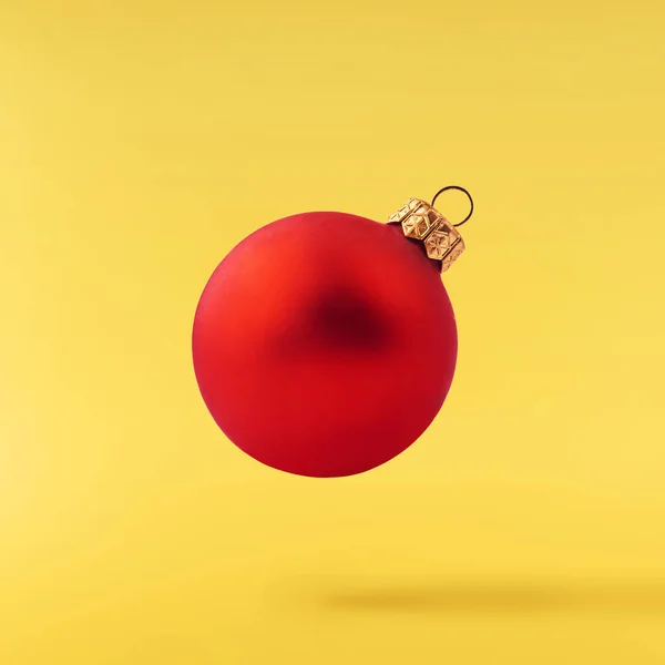 Christmas concept.  Creative Christmas conception made by falling in air shiny bauble over yellow background. Minimal concept