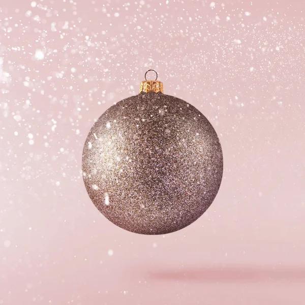 Christmas concept.  Creative Christmas conception made by falling in air shiny bauble over pink background. Minimal concept