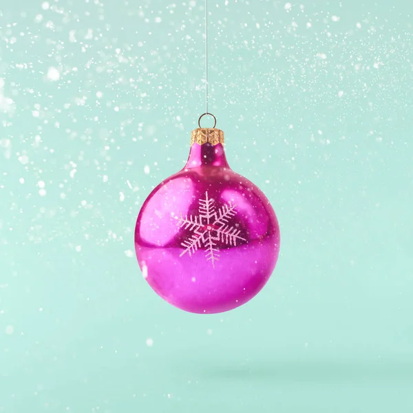 Christmas concept.  Creative Christmas conception made by falling in air shiny bauble over turquoise background. Minimal concept