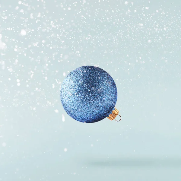 Christmas concept.  Creative Christmas conception made by falling in air shiny bauble over blue background. Minimal concept