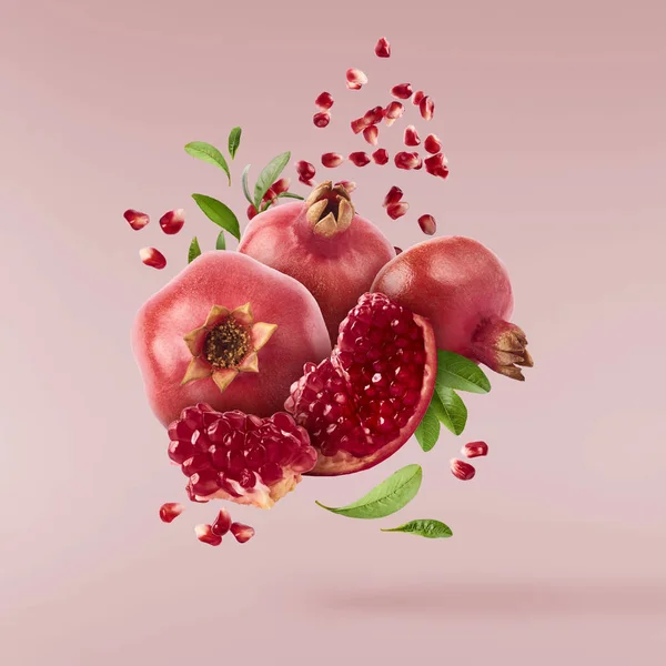 Hava taze olgun tüm ve kesme nar tohum ve pastel pembe izole yaprakları ile uçan. Yüksek çözünürlüklü görüntü