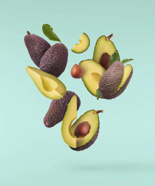 Verse rijpe avocado met bladeren die in de lucht vallen. — Stockfoto