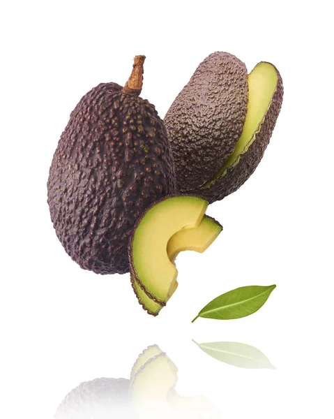 Verse rijpe avocado met bladeren die in de lucht vallen. — Stockfoto