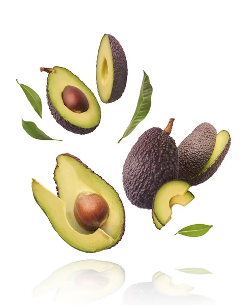 Verse rijpe avocado met bladeren die in de lucht vallen. — Stockfoto