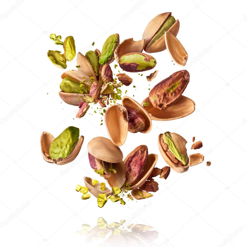 Flying in air fresh raw whole and cracked pistachios  isolated on white background. Concept of Pistachios is torn to pieces close-up. High resolution image