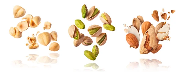 Beyaz arka planda taze çiğ bir bütün halinde uçan, fıstıkları, bademleri ve fındıkları kırılan bir set. Pistachios badem ve fındık kavramı yakın plan parçalanmıştır. Yüksek çözünürlük
