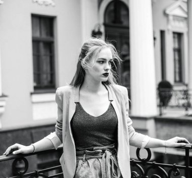 Genç ve güzel bir kız model şehirden uzağa bakıyor. Siyah beyaz gerçek fotoğraf. Sokak tarzı, moda, yaşam tarzı