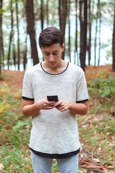 青少年在森林中使用手机 图库照片