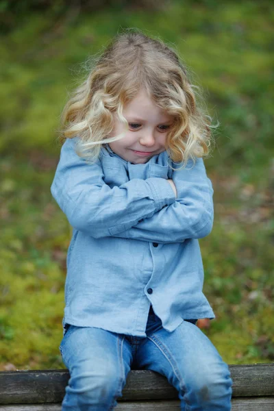 Arg Liten Pojke Med Långa Blonda Hår Sitter Utomhus Med — Stockfoto