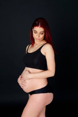 genç hamile kadın siyah arka plan üzerinde poz