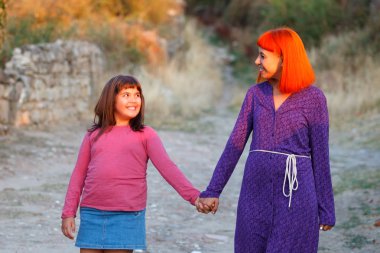 mutlu güzel kırmızı saçlı anne ve sevimli kızı parkta elele