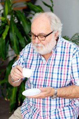 evde rahatlatıcı ve kahve içme beyaz sakallı üst düzey adam portresi 