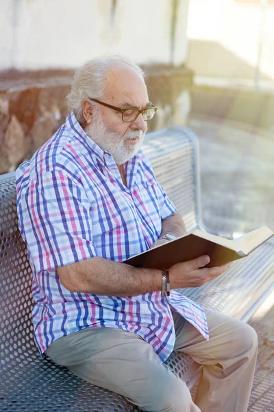 Starszy Człowiek Czytanie Książki Siedząc Ławce Ulicy — Zdjęcie stockowe