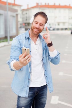 Casual adam yanındaki bir vintage Bisiklet kot gömlek giymiş kulaklık ile müzik dinleme