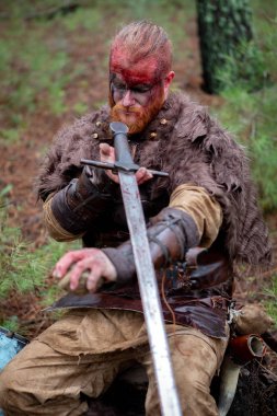 Gerçek viking kılıcını bir taşla keskinleştiriyor. Savaşa hazır