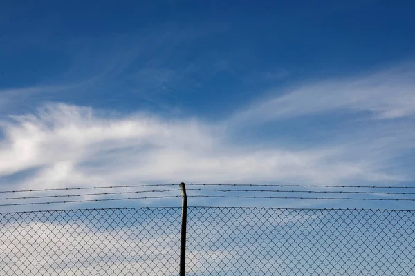 Cerca de arame com um céu azul com nuvens — Fotografia de Stock