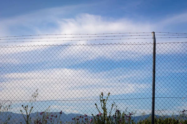 Draad hek met een blauwe lucht met wolken — Stockfoto