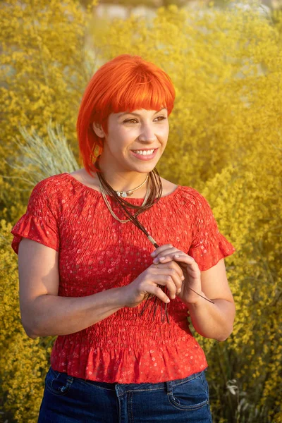 赤いシャツと花の田舎の自然の上を歩くバックパックを持つ魅力的な女性 — ストック写真
