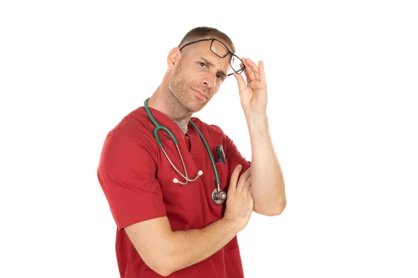 Médico bonito com uniforme vermelho levantando os óculos — Fotografia de Stock