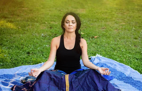 Bruneta žena dělá jógu v parku — Stock fotografie