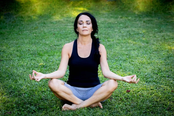 Brünette Frau macht Yoga in einem Park — Stockfoto