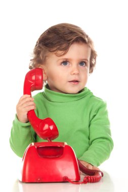 Bir yaşında bir bebek kırmızı bir telefonla oynuyor.