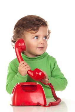 Bir yaşında bir bebek kırmızı bir telefonla oynuyor.